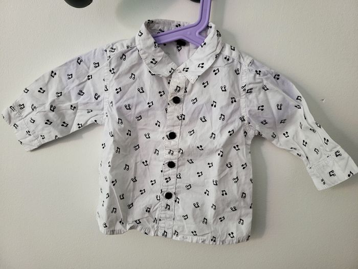 Chemise manches longues Chemise manches longues blanche avec des notes de musique noire, taille 6 mois, en très bon état.