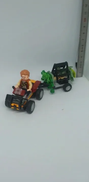 Owen dans véhicule quad avec remorque et bébé dinosaure raptor en cage lego