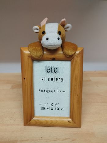 Cadre photo format 10 x 15 cm (4" x 6"), en bois, avec une peluche vache attachée sur le dessus. Parfait pour une chambre d'enfant