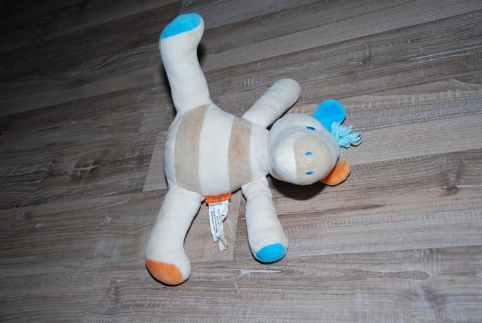 doudou zèbre cheval Marése blanc crème rayé bleu orange assis