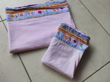 drap plat et taie d'oreiller lit barreaux couleur rose avec une bordure à fleurs