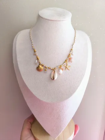 Collier doré et beige avec charms marins et fleur