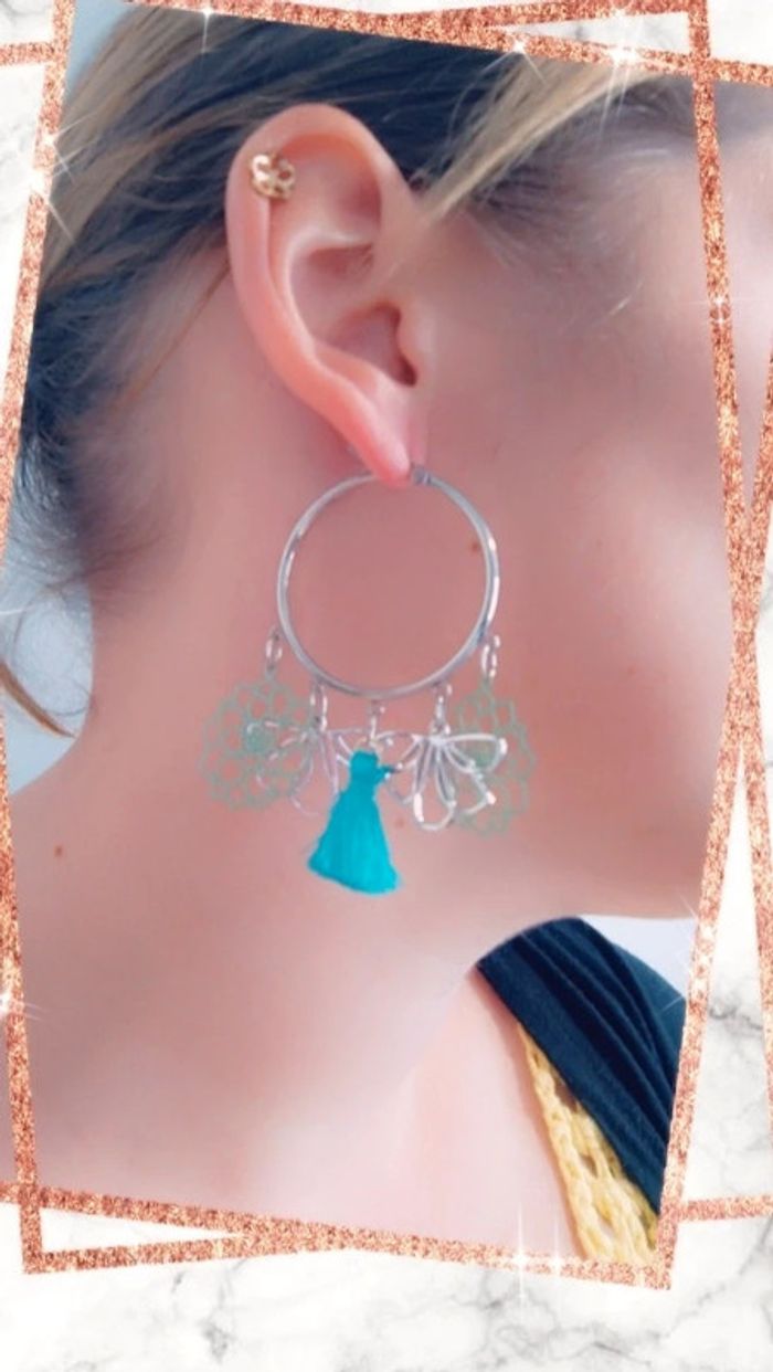 Créoles avec breloques argentées et pompons bleus.