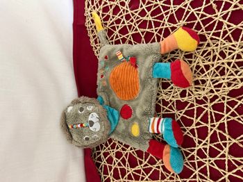 Doudou plat lion SIMBA TOYS gris cercle orange bandana bleu Nicotoy