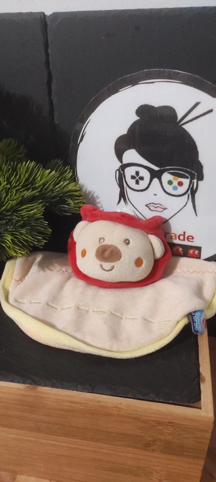 Doudou plat rond Lion beige vert rouge Sucre d'Orge marron