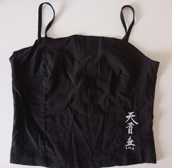 Débardeur noir avec des  bretelles. Taille S . Fermeture éclair. Signes chinois blancs . Viscose polyamide et élasthanne. Très bon état