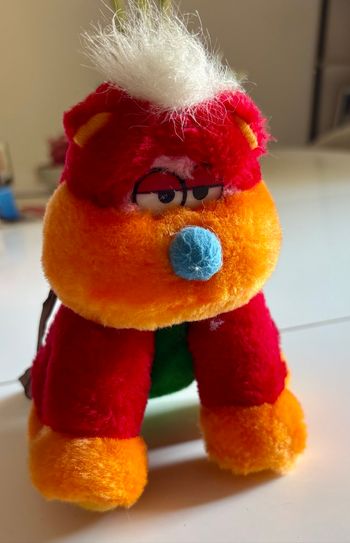 Peluche atypique assise colorée au regard nonchalant