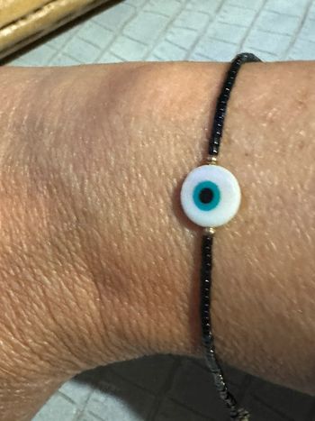 Bracelet réglable finitions acier inoxydable or perles naturelles noires œil résine