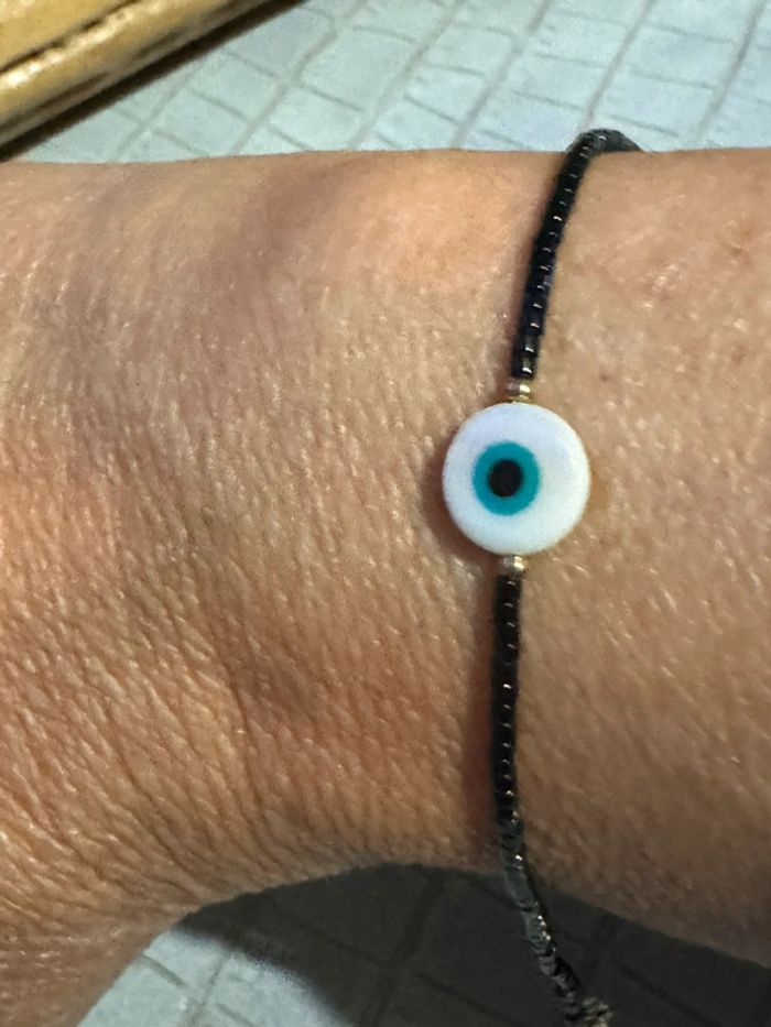 Bracelet réglable finitions acier inoxydable or perles naturelles noires œil résine