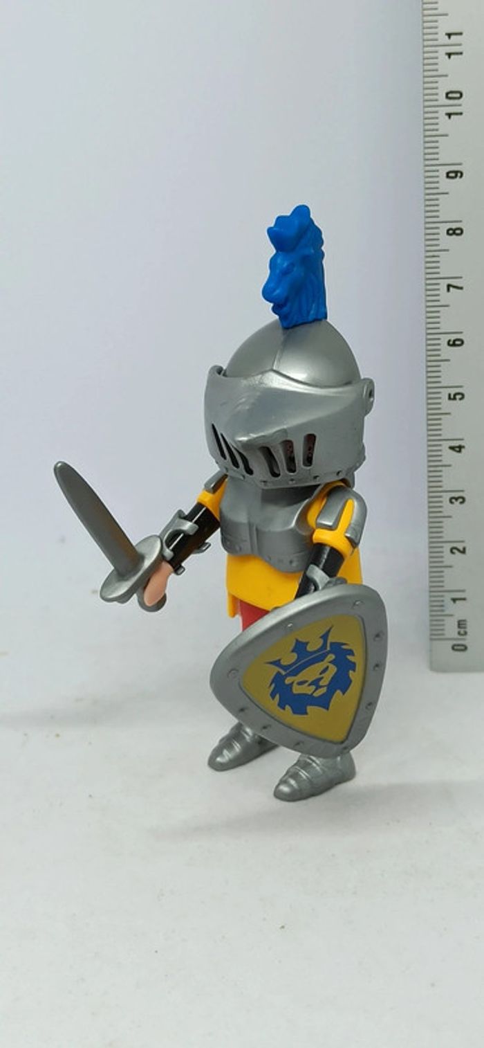 Homme chevalier avec petit lion bleu sur le casque et bouclier motif lion plume