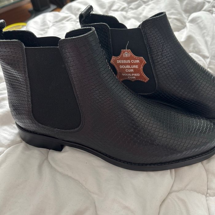 une bottine noire en cuir avec un effet texturé façon peau de serpent. 👢