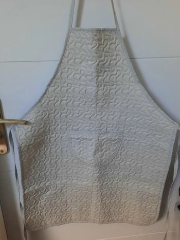 Tablier gris avec des arabesques.