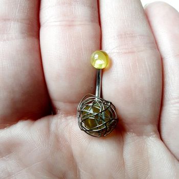 Piercing nombril jaune translucide encerclé de filaments
