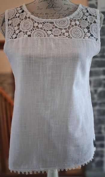 Blouse blanche avec le col en dentelle et zippée au dos