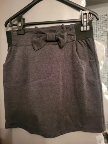 Jupe gris foncé avec nœud et boutons.