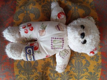 Doudou Ajena ours ourson blanc tissu bouclettes éponge corps imprimé fruit chapeau