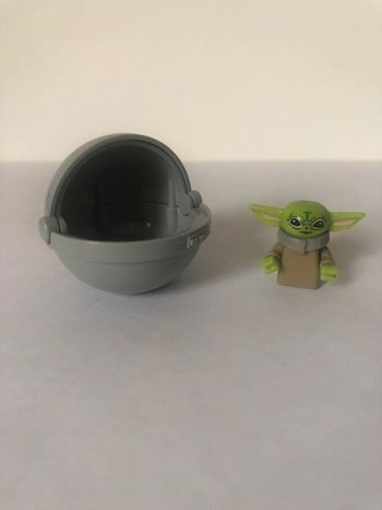 Figurine type lego Grogu dans la capsule. Star Wars
