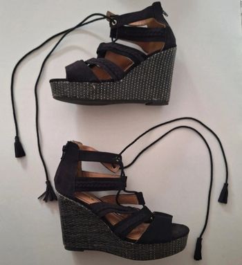 Sandales compensées noires à hauts talons et lacets à pompons