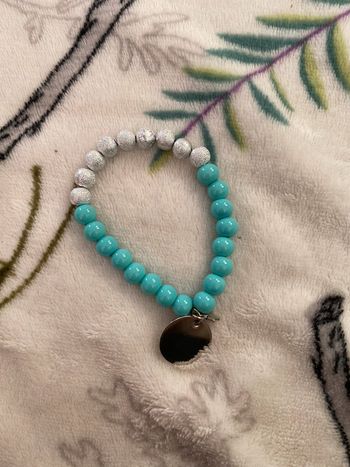 Bracelet perles argentées et bleues et breloques rond et étoile.