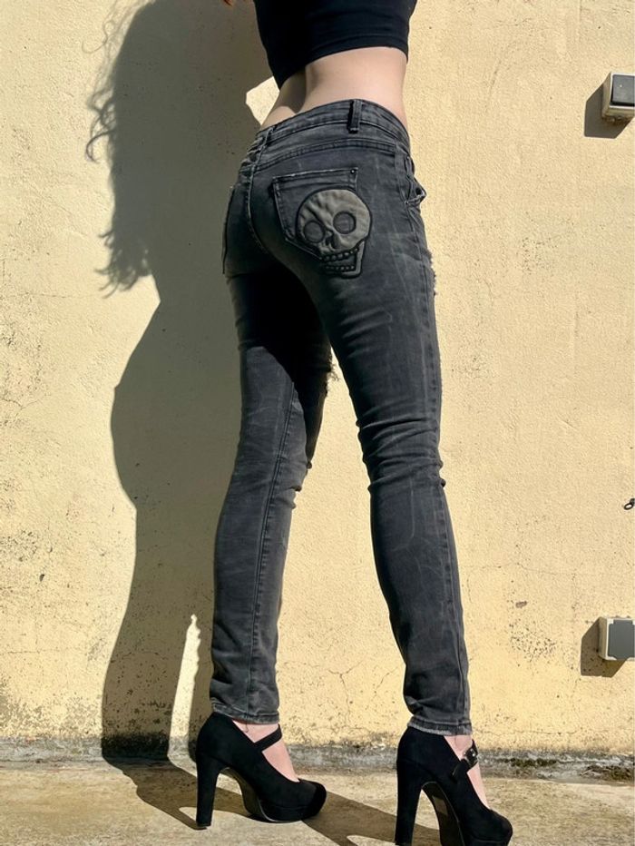 Jean troué taille basse gris nuancé, motif tête de mort sur poche arrière.