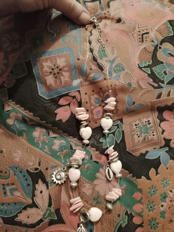 collier en métal argenté et perles en plastique roses claires.