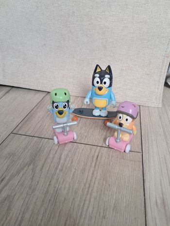 Figurines bluey et bingo qui font de la trottinette et bandit avec son skate