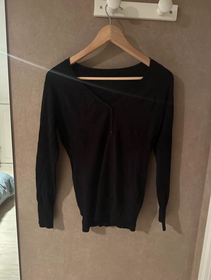 Pull noir avec des boutons sur le devant
