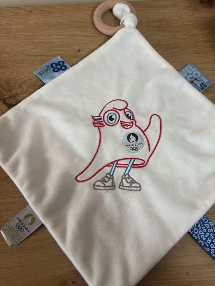 Neuf doudou plat mouchoir mascotte jo Paris 2024 anneau bois - photo numéro 2