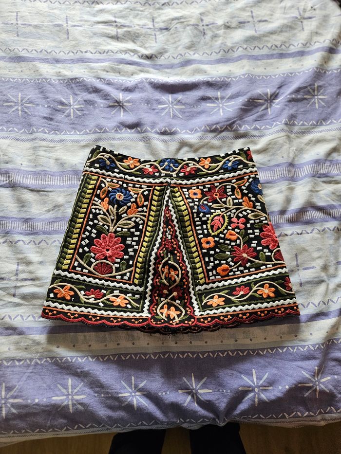 Jupe fond noire, fleur orange liseré bordeaux en bas.