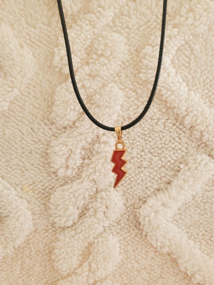 Collier avec un pendentif doré et rouge en forme d'éclair
