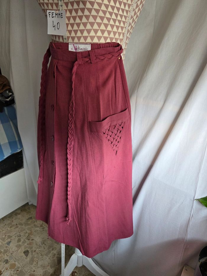 Jupe, rose/bordeaux, en excellent état, en polyester/viscose/lin, fermeture dos par zip& bouton, ceinture élastique + cordon décoratif, 2 poches avec déco, largeur de taille 35cm, longueur 72cm, marque Armand Thiery =8€