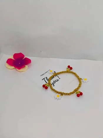 Bracelet doré élastique avec breloques cerises et marguerites blanches
