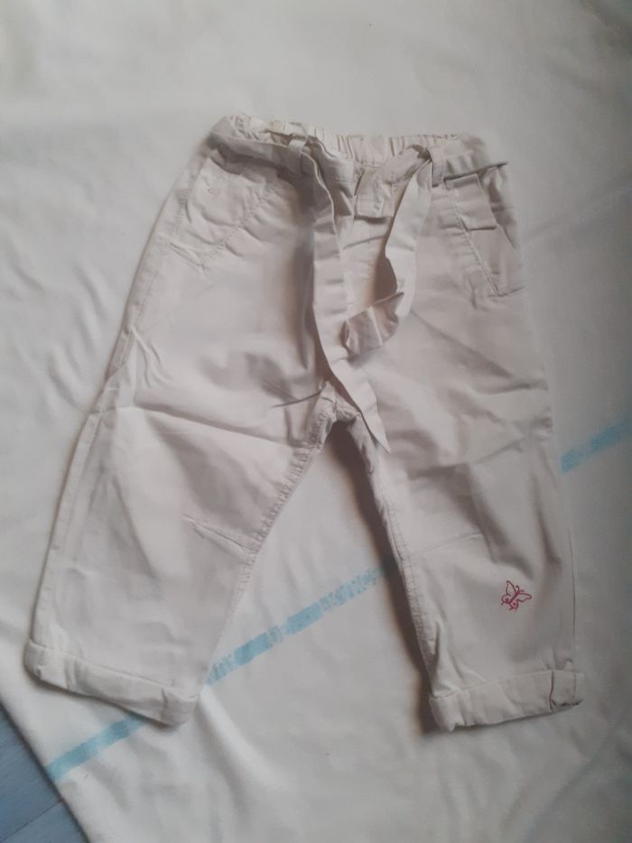 Pantalon blanc avec ceinture à la taille et petit papillon rouge au bas