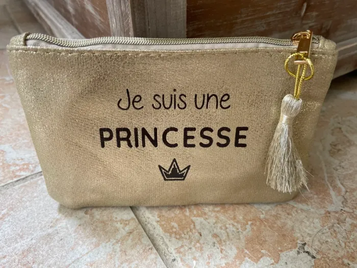 pochette dorée zippée avec inscription et pompom