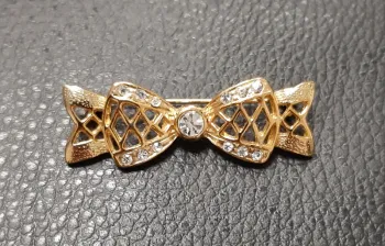 Très belle broche en metal doré et strass en forme de noeud