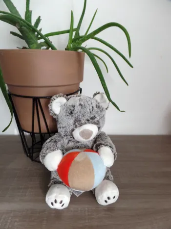 Nounours en peluche gris musical qui tient un ballon