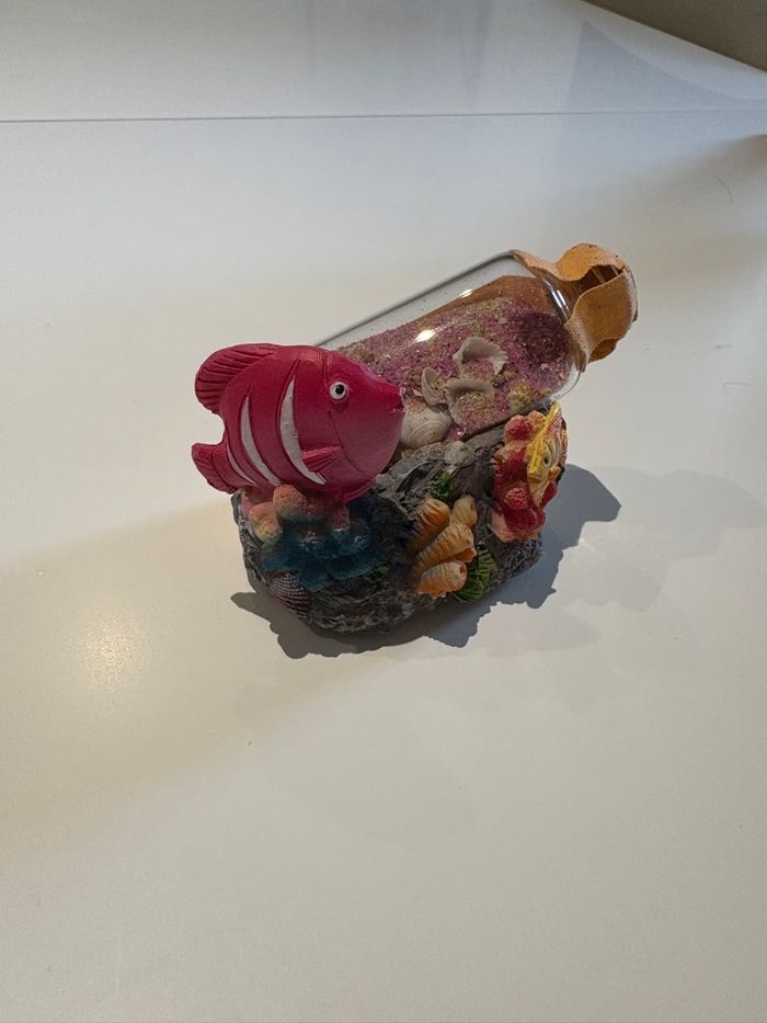 Objet de décoration sur le thème de la mer avec une bouteille de verte contenant du sable rose