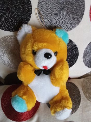 Peluche doudou ours ourson assis jaune ventre blanc une oreille bleue vintage ancien une oreille  intérieur blznc nez noir plastique dur noeud pap  noir au cou 