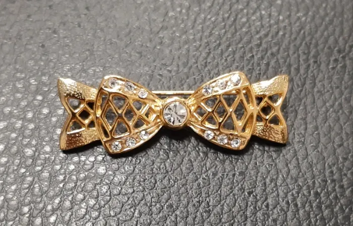 Très belle broche en metal doré et strass en forme de noeud