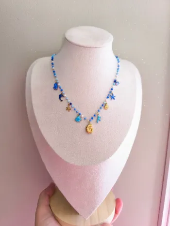 Collier doré et bleu avec perles de cristal et breloques de la mer