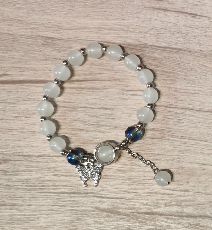 Bracelet élastique avec perles blanches et pendentif papillon argenté et zirconiums