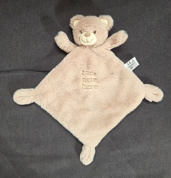 Doudou plat ours losange en velours fourrure de couleur beige . 
Visage brodé de fil de couleur marron.
Écriture brodé sur le doudoj de couleur beige " I am new here "