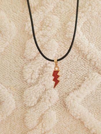 Collier avec un pendentif doré et rouge en forme d'éclair