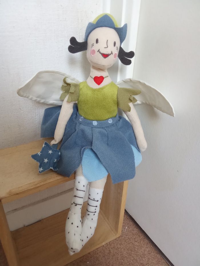 doudou poupée, fée, marque  ikea, corps souple, collier coeur rouge, ailes blanches, étoile bleue pois blancs dans la main, robe bleue, pull bonnet vert
