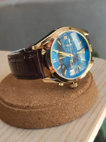 Montre marron, dorée, arrondie à reflets bleus