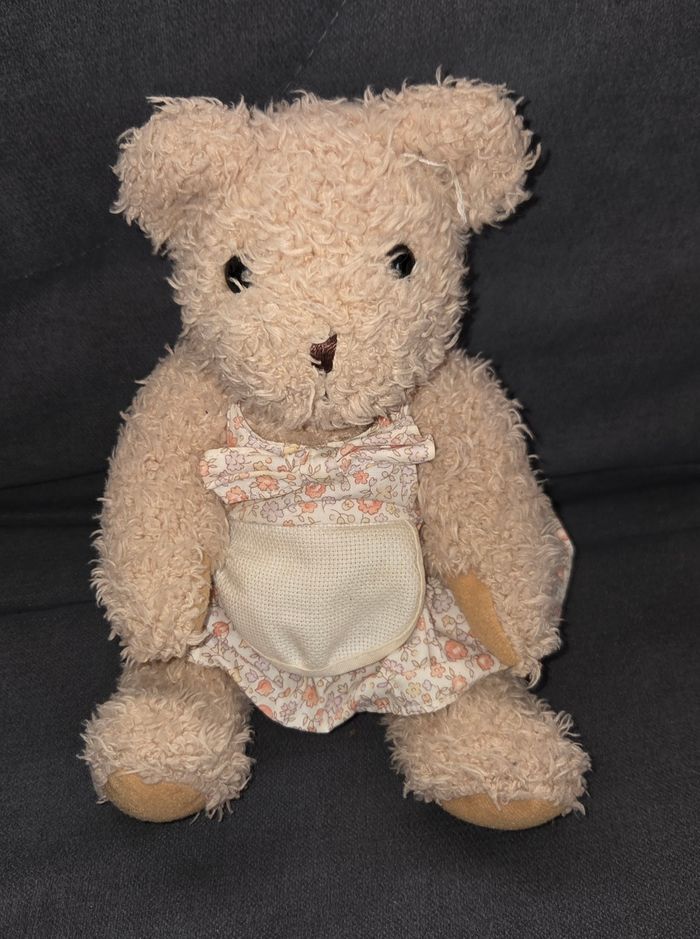 Doudou peluche ours robe fleuri - Tablier a brodé- DMCDoudou peluche ours en velours poils de couleur beige .
Ours qui mesure en position assise 20 cm .
Vêtue d'une robe en tissu fleuri et par dessus tablier a brodé.