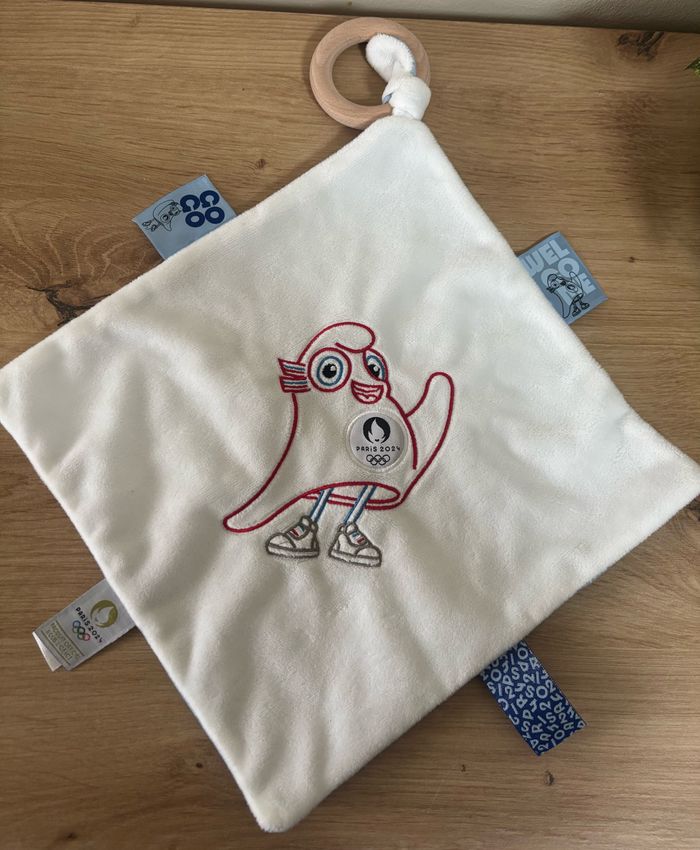 Neuf doudou plat mouchoir mascotte jo Paris 2024 anneau bois