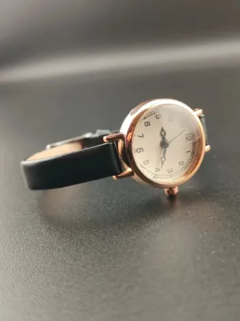 Montre ronde fine noire, dorée, discrète, précise