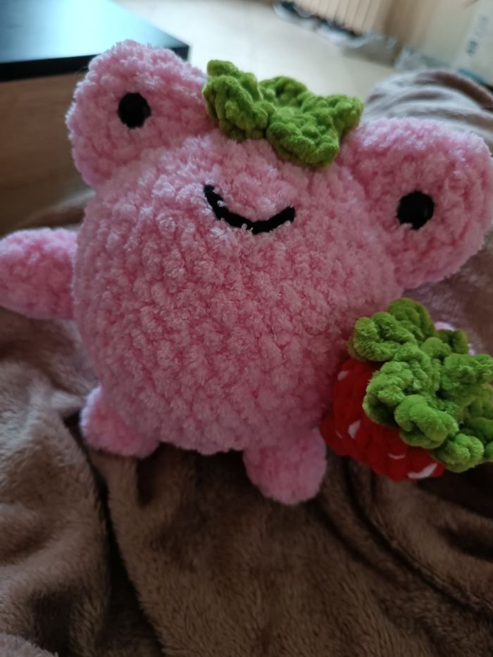 Peluche en forme de grenouille tenant une fraise