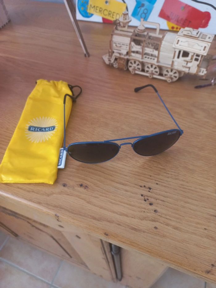 Une paire de lunettes de soleil ricard avec sa housse